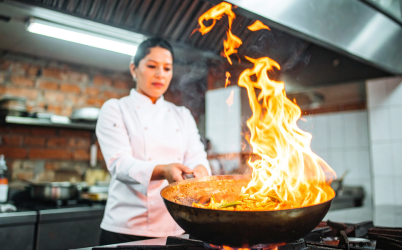 Chef preparing food over high heat in a professional kitchen, highlighting the intensity and complexity of F&B operations