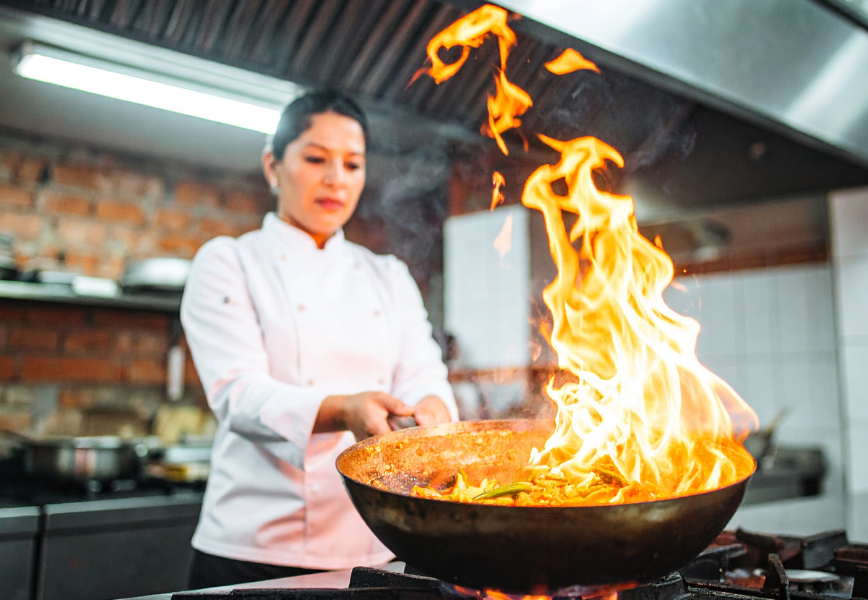Chef preparing food over high heat in a professional kitchen, highlighting the intensity and complexity of F&B operations