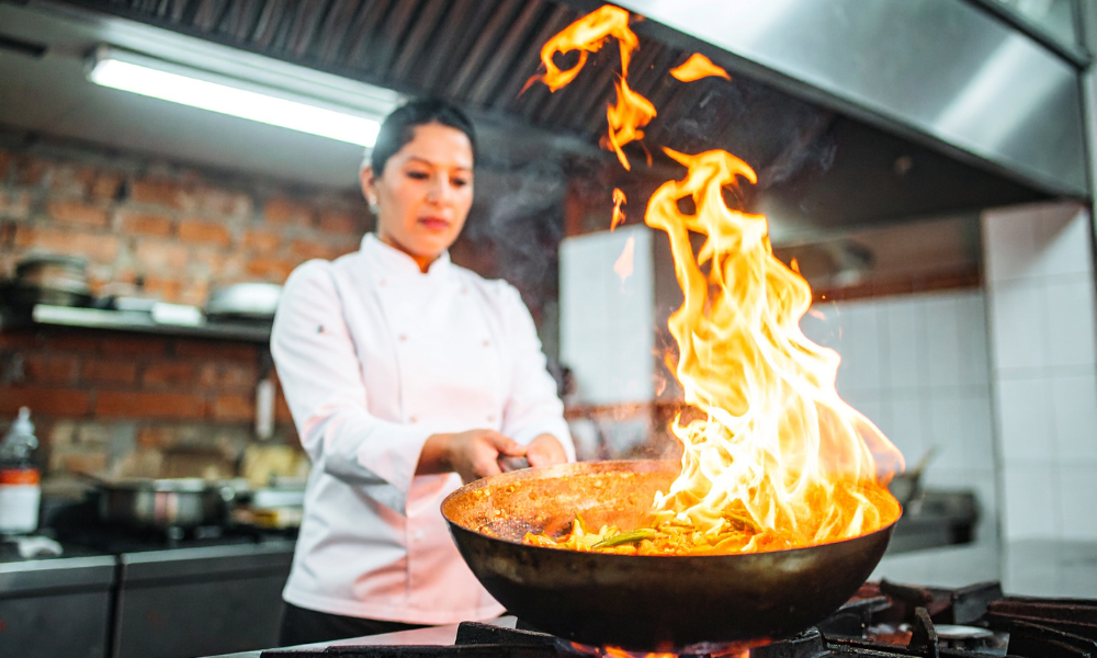Chef preparing food over high heat in a professional kitchen, highlighting the intensity and complexity of F&B operations